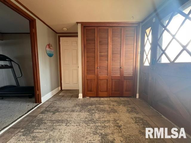 unfurnished bedroom with tile patterned flooring, ornamental molding, and a closet