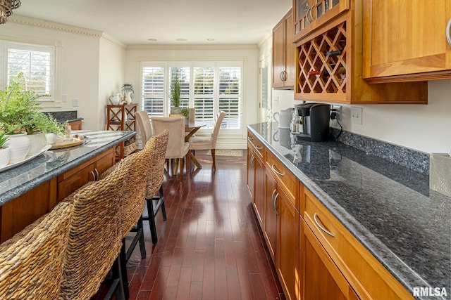 kitchen featuring ornamental molding, dark hardwood / wood-style floors, and dark stone countertops