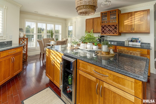 kitchen featuring crown molding, dark hardwood / wood-style floors, a kitchen island, beverage cooler, and dark stone counters