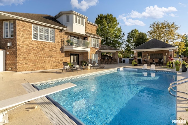 view of swimming pool featuring a bar, a diving board, and a patio