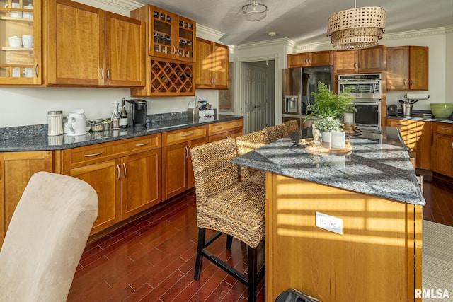 kitchen featuring decorative light fixtures, a center island, dark stone countertops, ornamental molding, and appliances with stainless steel finishes