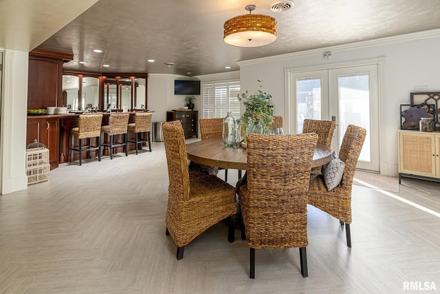 dining space with french doors, light parquet flooring, ornamental molding, and a textured ceiling