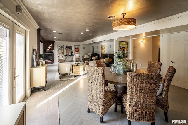 dining area with crown molding, light parquet flooring, and a textured ceiling