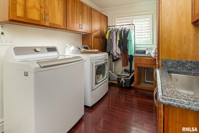 clothes washing area featuring dark hardwood / wood-style floors, sink, crown molding, cabinets, and washing machine and dryer