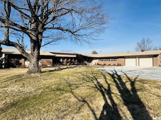 ranch-style house featuring a garage, driveway, brick siding, and a front yard