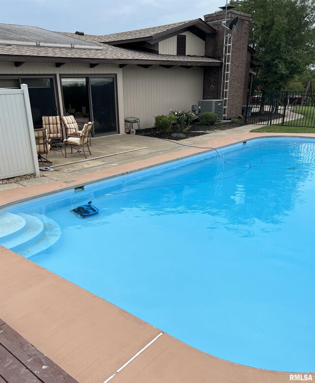 view of swimming pool featuring a fenced in pool, a patio area, fence, and central AC