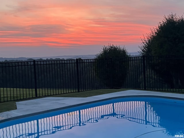 pool at dusk with a fenced in pool and a fenced backyard