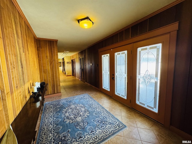 tiled foyer featuring wooden walls, crown molding, and french doors