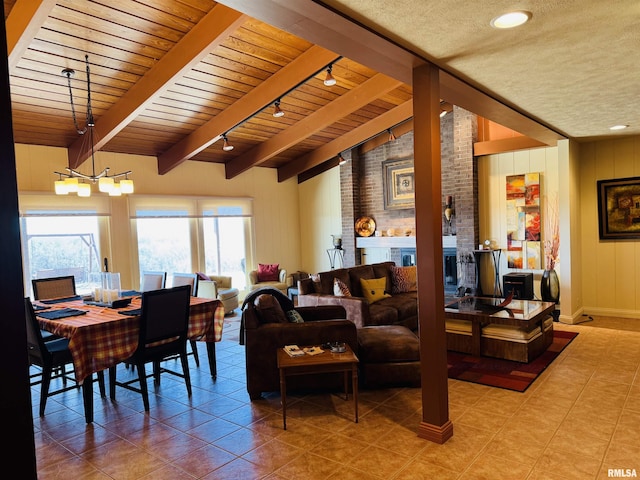 living room with a textured ceiling, vaulted ceiling with beams, a brick fireplace, and tile patterned floors