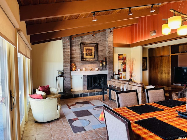 living area with vaulted ceiling with beams, a fireplace, tile patterned flooring, and wooden walls