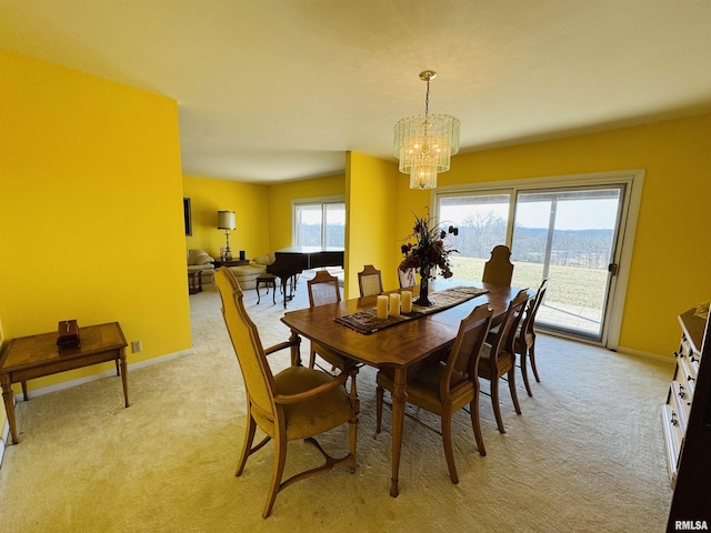 dining area with light colored carpet, baseboards, and an inviting chandelier