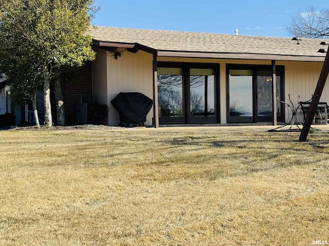 property entrance with a shingled roof and a lawn