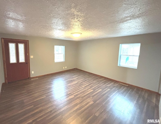 spare room featuring a textured ceiling and dark hardwood / wood-style flooring