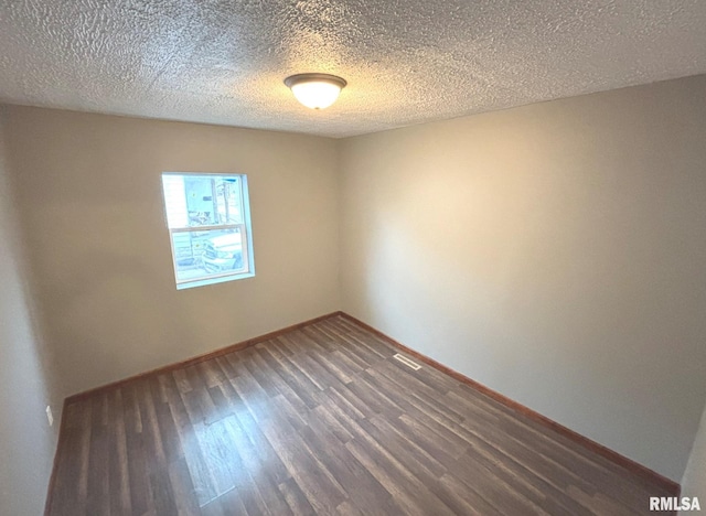 empty room featuring dark hardwood / wood-style floors and a textured ceiling