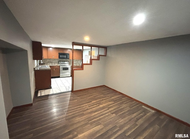 unfurnished living room featuring sink and dark wood-type flooring