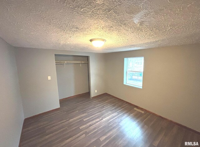 unfurnished bedroom featuring dark hardwood / wood-style flooring, a closet, and a textured ceiling