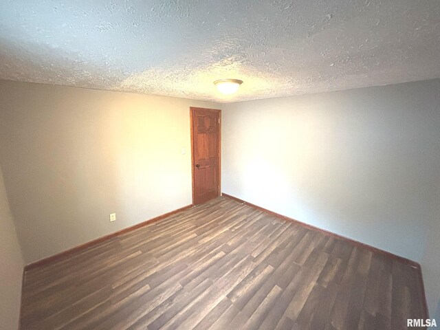 unfurnished room with dark hardwood / wood-style flooring and a textured ceiling