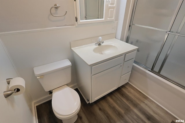full bathroom featuring vanity, hardwood / wood-style floors, shower / bath combination with glass door, and toilet