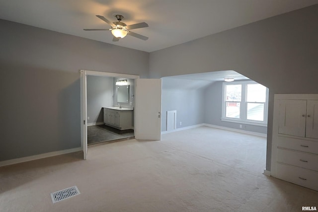 additional living space featuring ceiling fan, sink, and light carpet