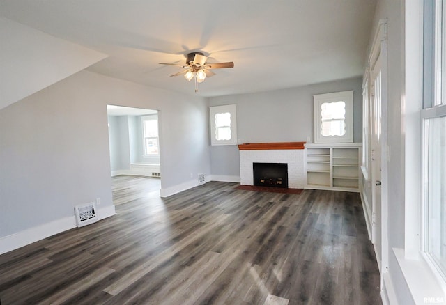 unfurnished living room featuring ceiling fan, dark hardwood / wood-style flooring, and a brick fireplace