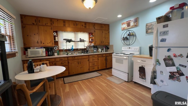 kitchen with white appliances, sink, and light wood-type flooring