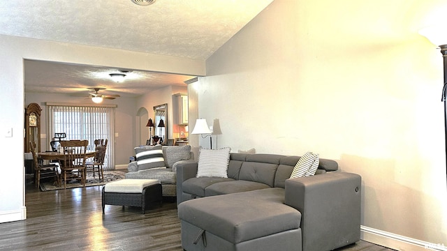 living room featuring ceiling fan, dark hardwood / wood-style flooring, and a textured ceiling