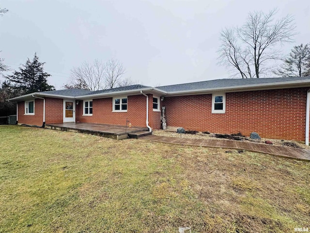 rear view of property with a wooden deck and a lawn