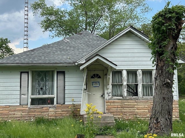 view of front of property with a shingled roof and stone siding