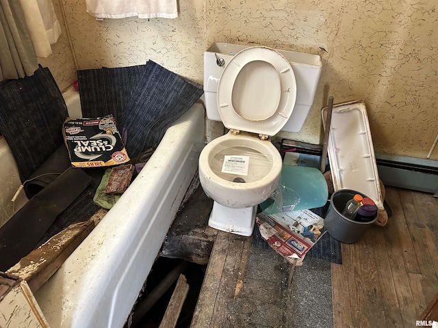 bathroom with a tub to relax in, hardwood / wood-style floors, and toilet