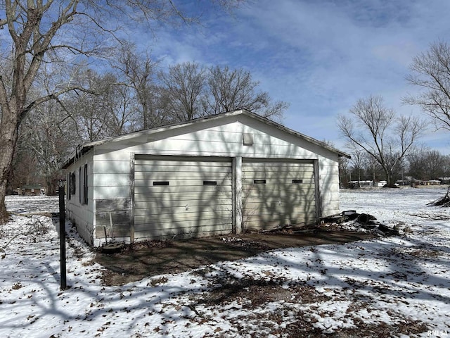 snow covered structure with a garage