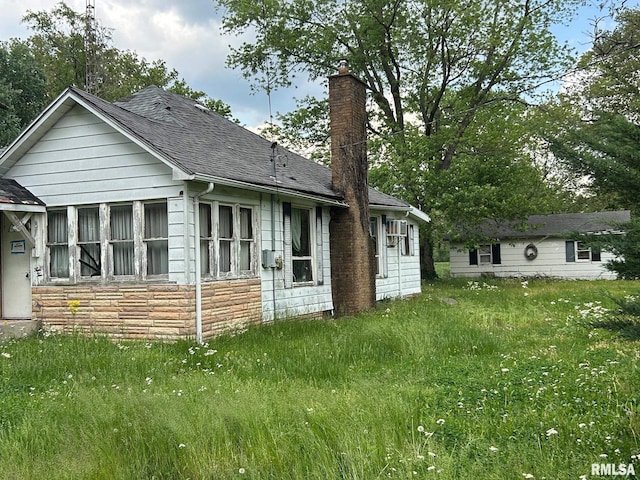 view of side of property with a shingled roof, a chimney, and stone siding