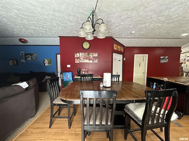 dining room with a chandelier, light hardwood / wood-style flooring, and a textured ceiling