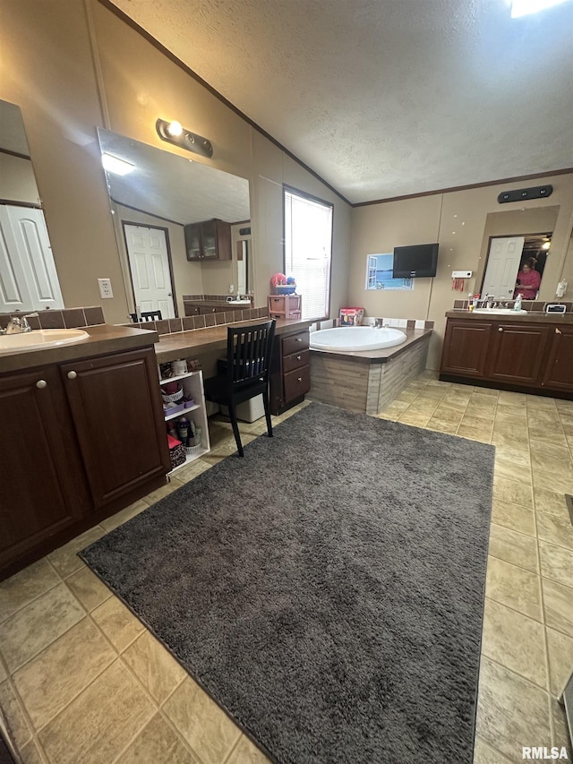 bathroom with tile patterned flooring, vanity, a textured ceiling, a tub to relax in, and vaulted ceiling