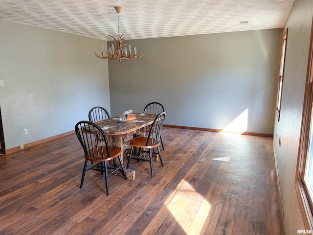 dining space featuring dark hardwood / wood-style flooring, a textured ceiling, and a notable chandelier