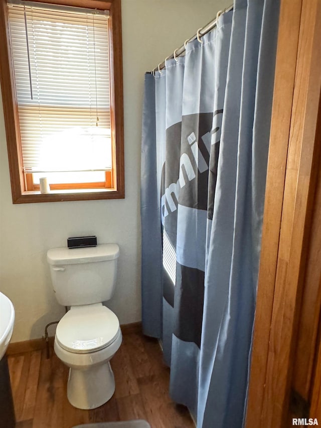 bathroom featuring hardwood / wood-style flooring, walk in shower, and toilet