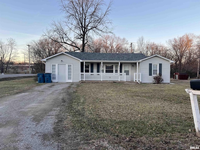 single story home with covered porch, dirt driveway, roof with shingles, and a front yard