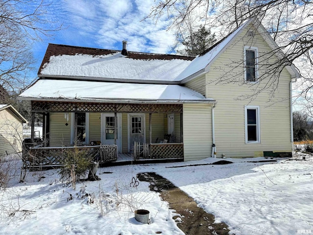 snow covered back of property with covered porch