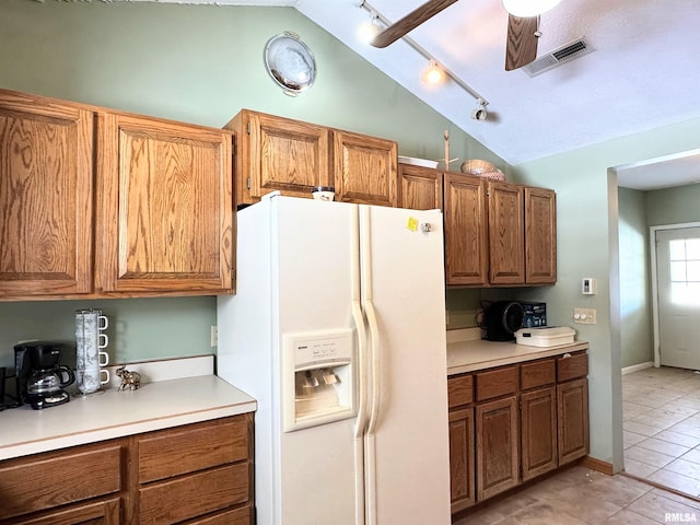 kitchen featuring light countertops, visible vents, lofted ceiling, white refrigerator with ice dispenser, and brown cabinetry