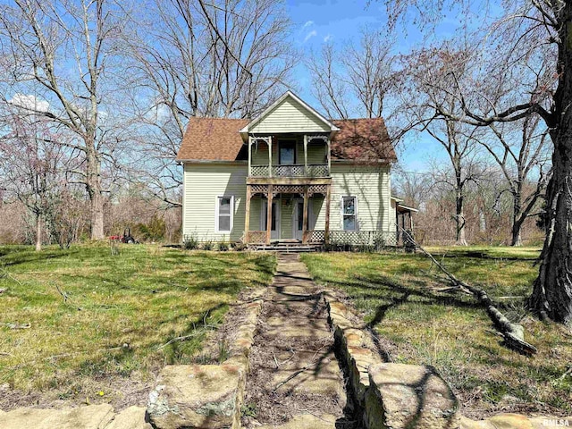 victorian house featuring a balcony and a front yard