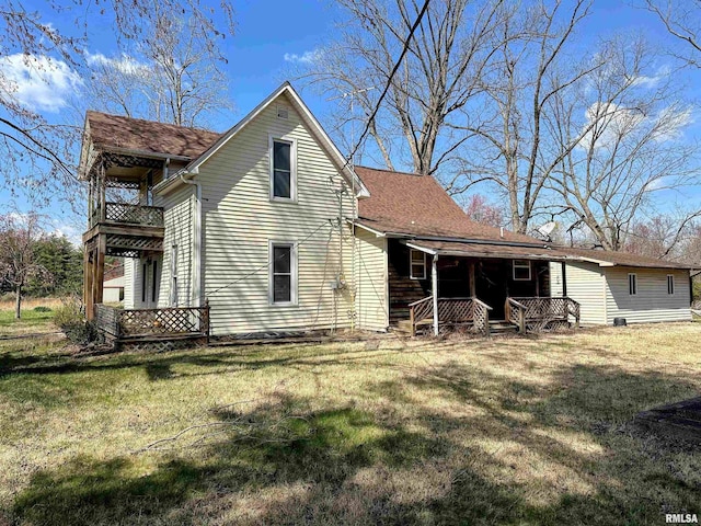 rear view of house featuring a balcony, a porch, and a yard
