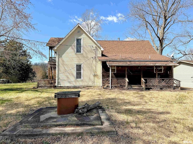 rear view of property featuring a shingled roof, a porch, and a yard