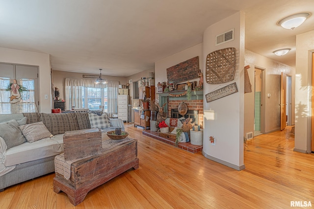 living room with a brick fireplace and light hardwood / wood-style flooring