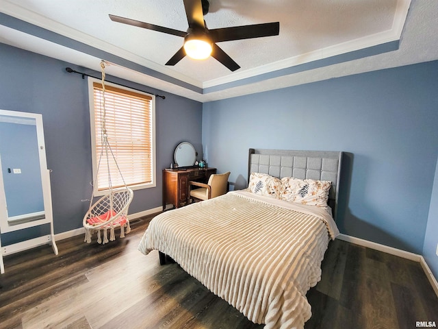 bedroom with a raised ceiling, hardwood / wood-style flooring, ceiling fan, and a textured ceiling