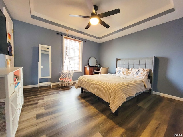 bedroom with ceiling fan, dark wood-type flooring, and a raised ceiling