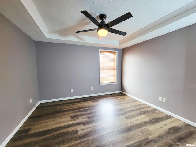 spare room with a tray ceiling, ceiling fan, dark hardwood / wood-style flooring, and a textured ceiling