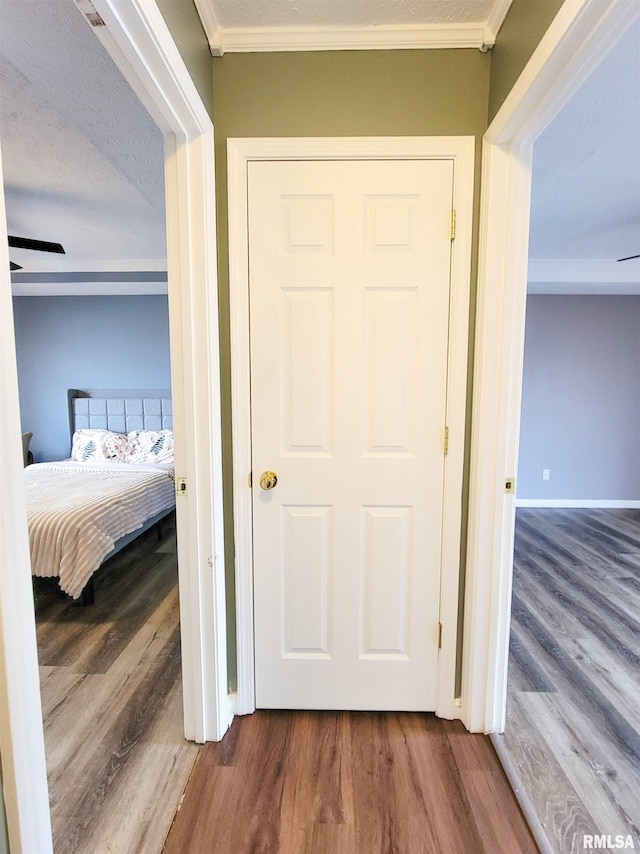 hall featuring crown molding, wood-type flooring, and a textured ceiling