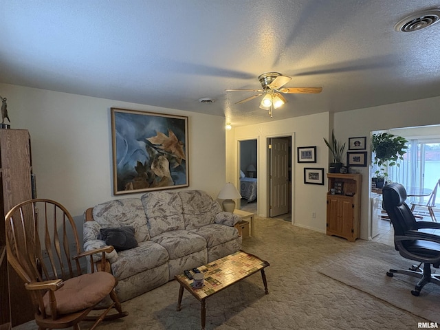 carpeted living room with ceiling fan and a textured ceiling