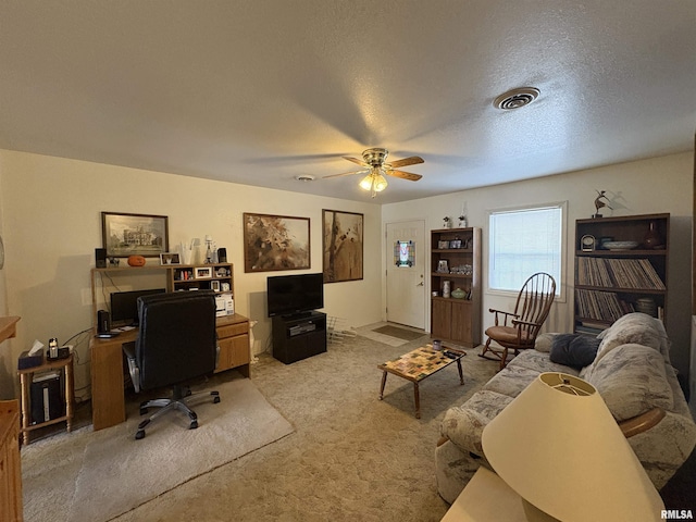 carpeted office space with a textured ceiling and ceiling fan