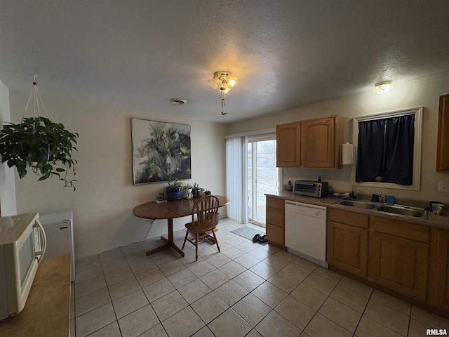 kitchen featuring sink, dishwasher, a textured ceiling, and light tile patterned floors