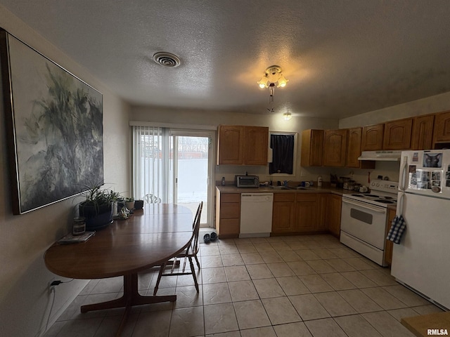 kitchen with sink, white appliances, a textured ceiling, and light tile patterned floors